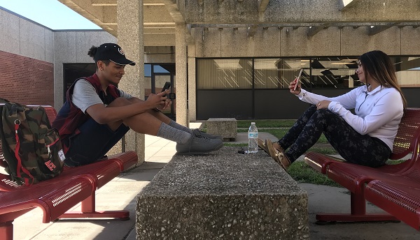 Imani Lemon and Adriana Nunez check social media in the courtyard at Allens Iola campus.