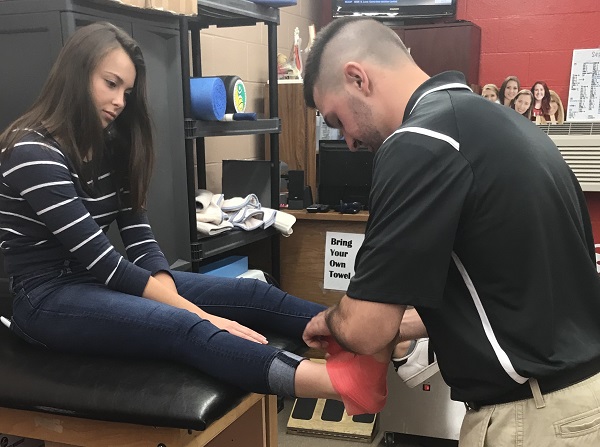 Athletic trainer Shane Venteicher tapes the ankle of Samantha Gulley before soccer practice.
