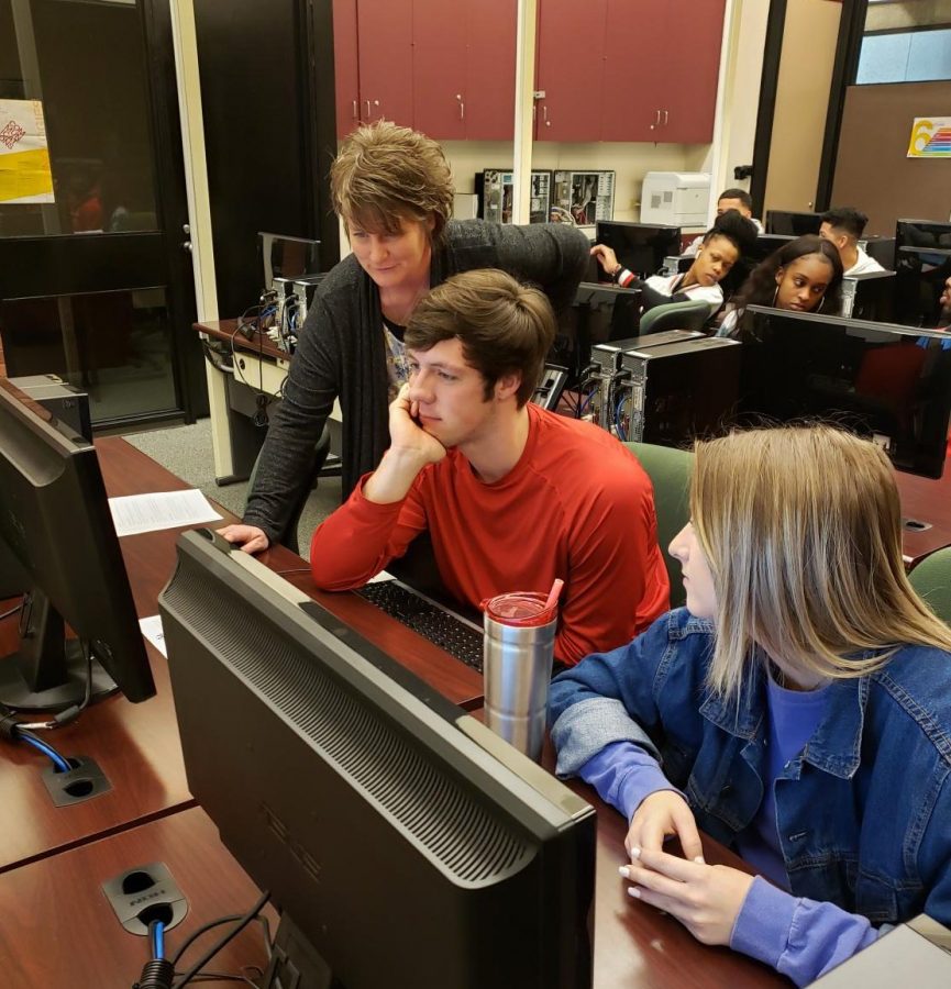 Business Instructor Nicci Denny assists students Brock Barkhurst and Emma Weseloh during the intro to business class at Allen Community College.
