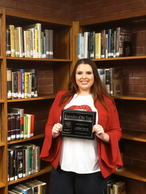 Lindsey Temaat smiles in the Allen Community College Library with her 2019 Journalist of the Year award. 