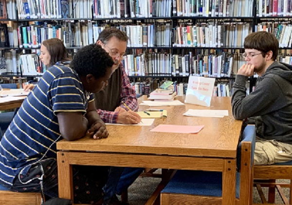 Jerry Vincent, Math Center coordinator, tutors a student while student tutor Noah Westervelt, right, looks on. Writing tutor Lexy Turntine is in the far left.