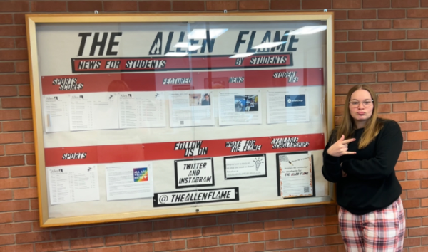 Alyssa Winsler, Student Reporter for The Allen Flame, poses with the The Allen Flame news board in the B wing of Allens main building. 